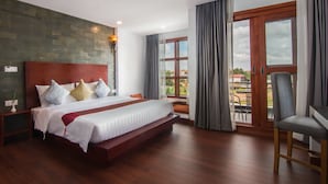 A modern hotel room with a large bed, wooden flooring, a balcony with a view, and a dining area. - Eco Villa (Siem Reap)