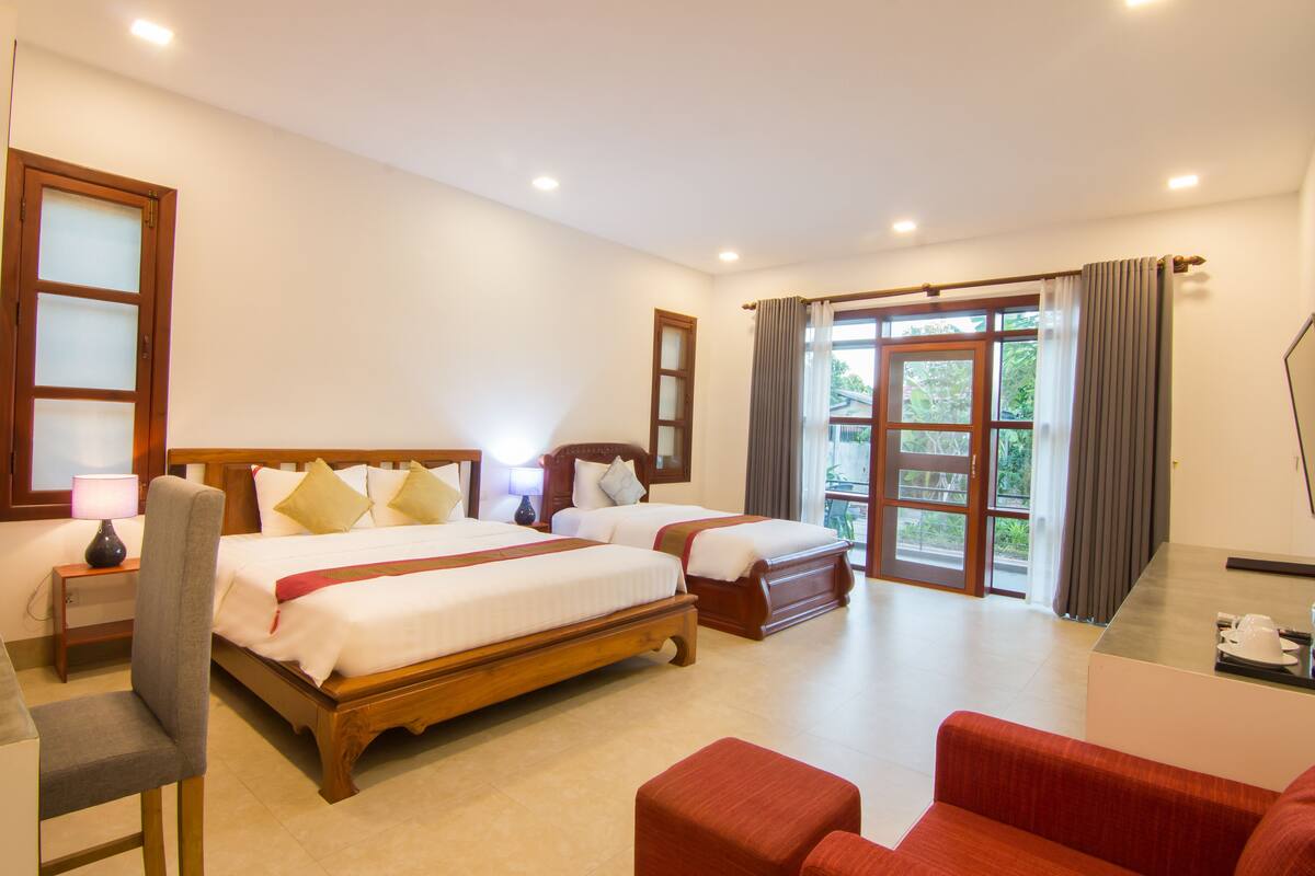 A hotel room with two beds, a desk, a chair, and a sofa.