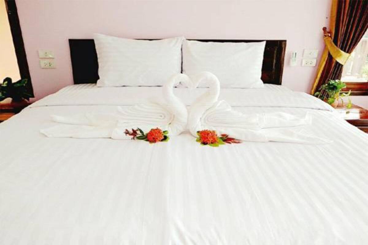 A bed with a white bedspread and two swan-shaped pillows.
