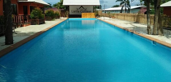 A swimming pool with a sign reading "Lanta Cotage" in the background. - Lanta Cottage (Ko Lanta)