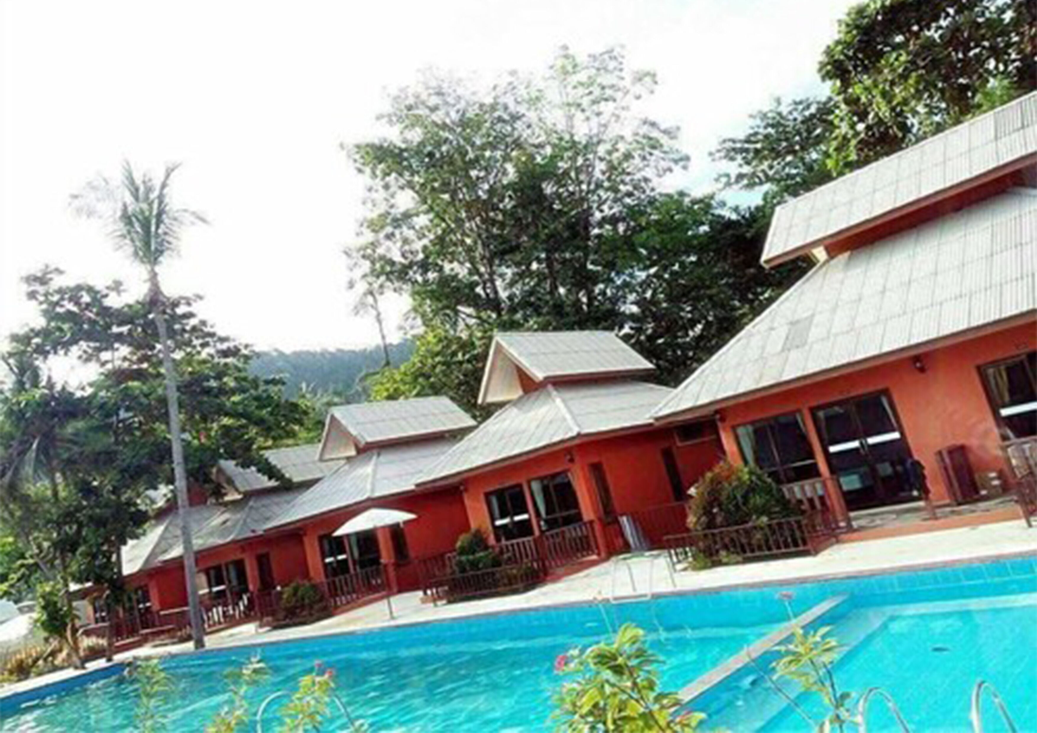 A row of red-roofed buildings with a swimming pool in the foreground.