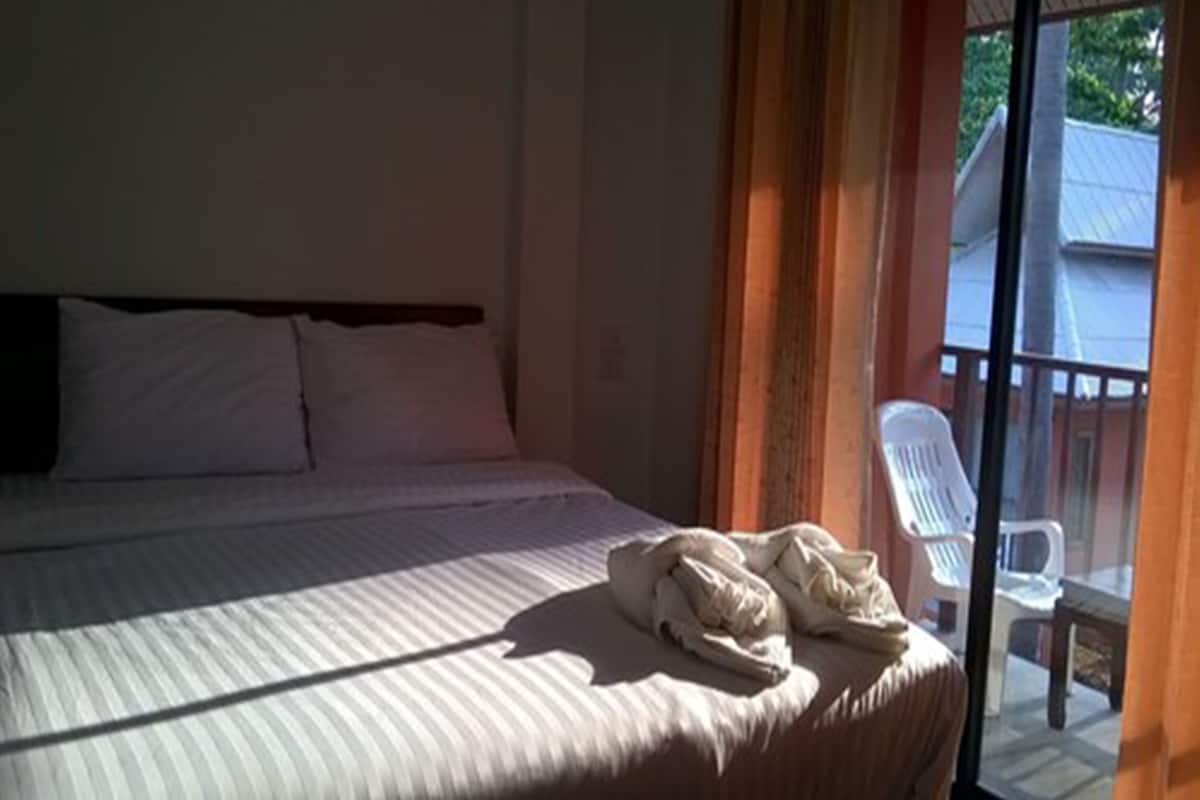 A hotel room with a bed, a window with curtains, and a view of the outside.