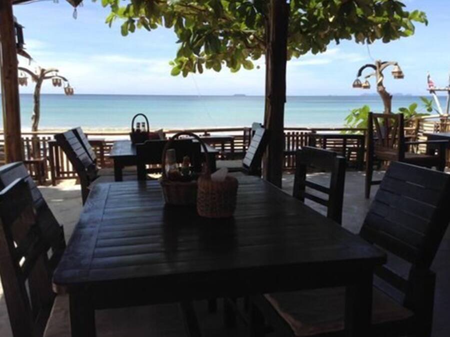 Un área de estar al aire libre con una mesa y sillas, con vista a la playa.