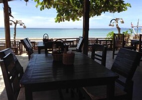 Un área de estar al aire libre con una mesa y sillas, con vista a la playa.
