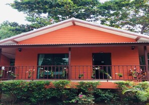 A red building with a balcony, potted plants, and a door. - Lanta Cottage (Ko Lanta)
