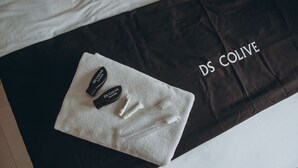 A black and white towel with DS COLIVE branded items on a bed. - DS Residence Sinabung (Semarang)