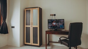 A room with a wooden wardrobe, a desk with a computer monitor, and a black office chair. - DS Residence Sinabung (Semarang)