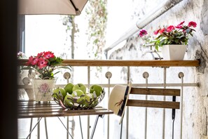 A balcony with a table holding a basket of green apples and a potted plant with pink flowers. - Centro di Centri Rooms (Split)