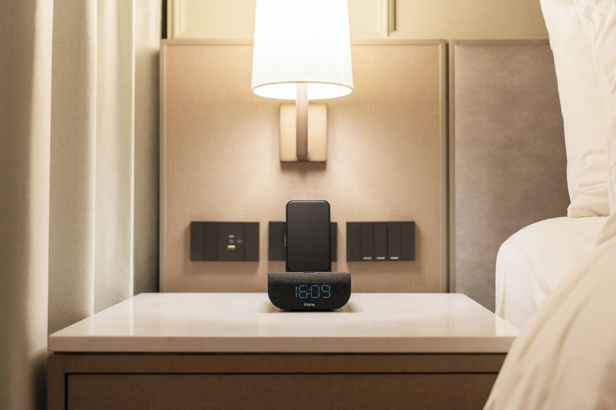 A modern bedside table with a digital clock displaying 16:09, a lamp, and a control panel.