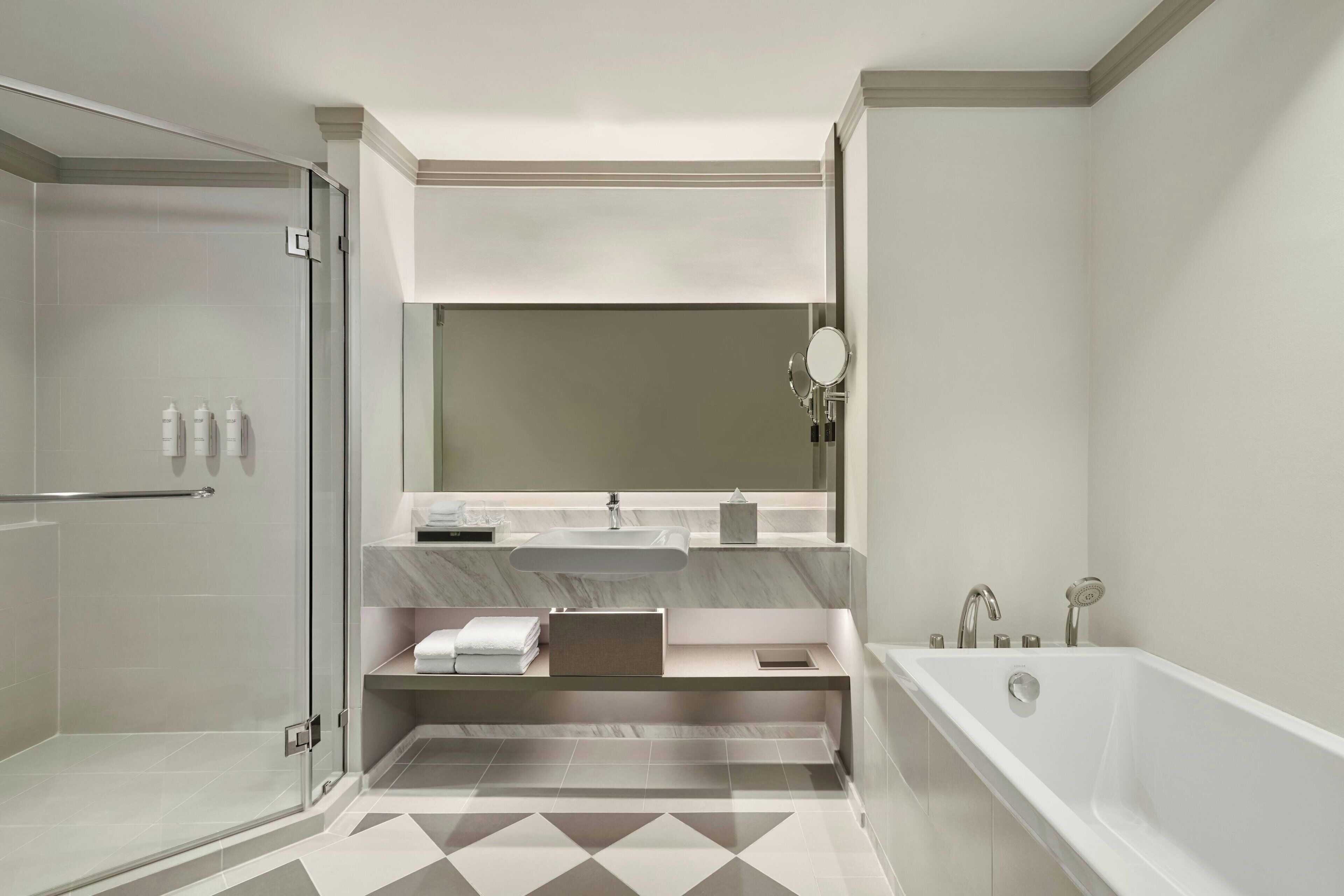 A modern bathroom with a glass shower enclosure, a freestanding bathtub, and a vanity with a large mirror.