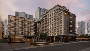 A modern hotel with a curved facade, multiple balconies, and a well-lit entrance.