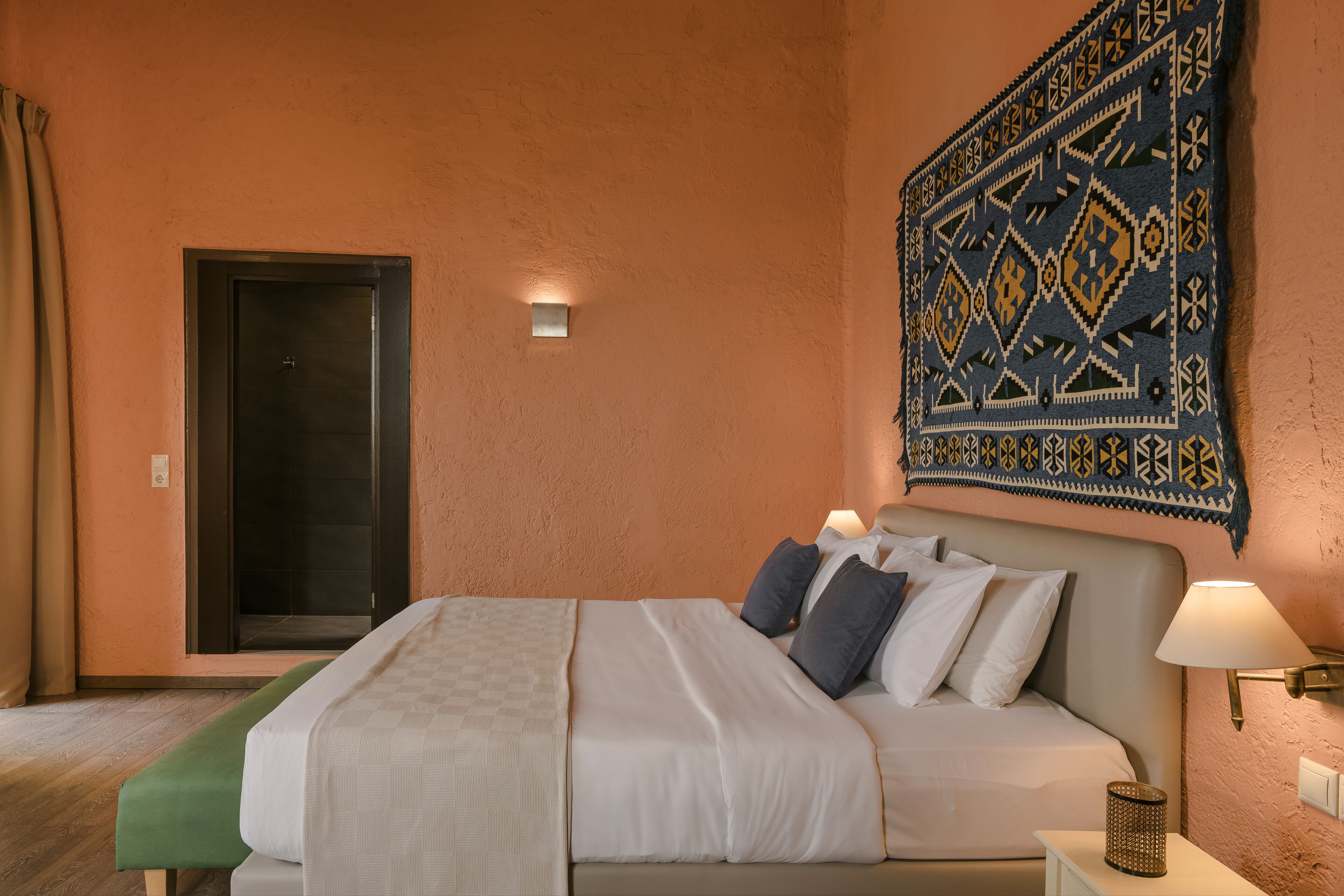 A neatly made bed with pillows, a bedside lamp, and a wall tapestry.