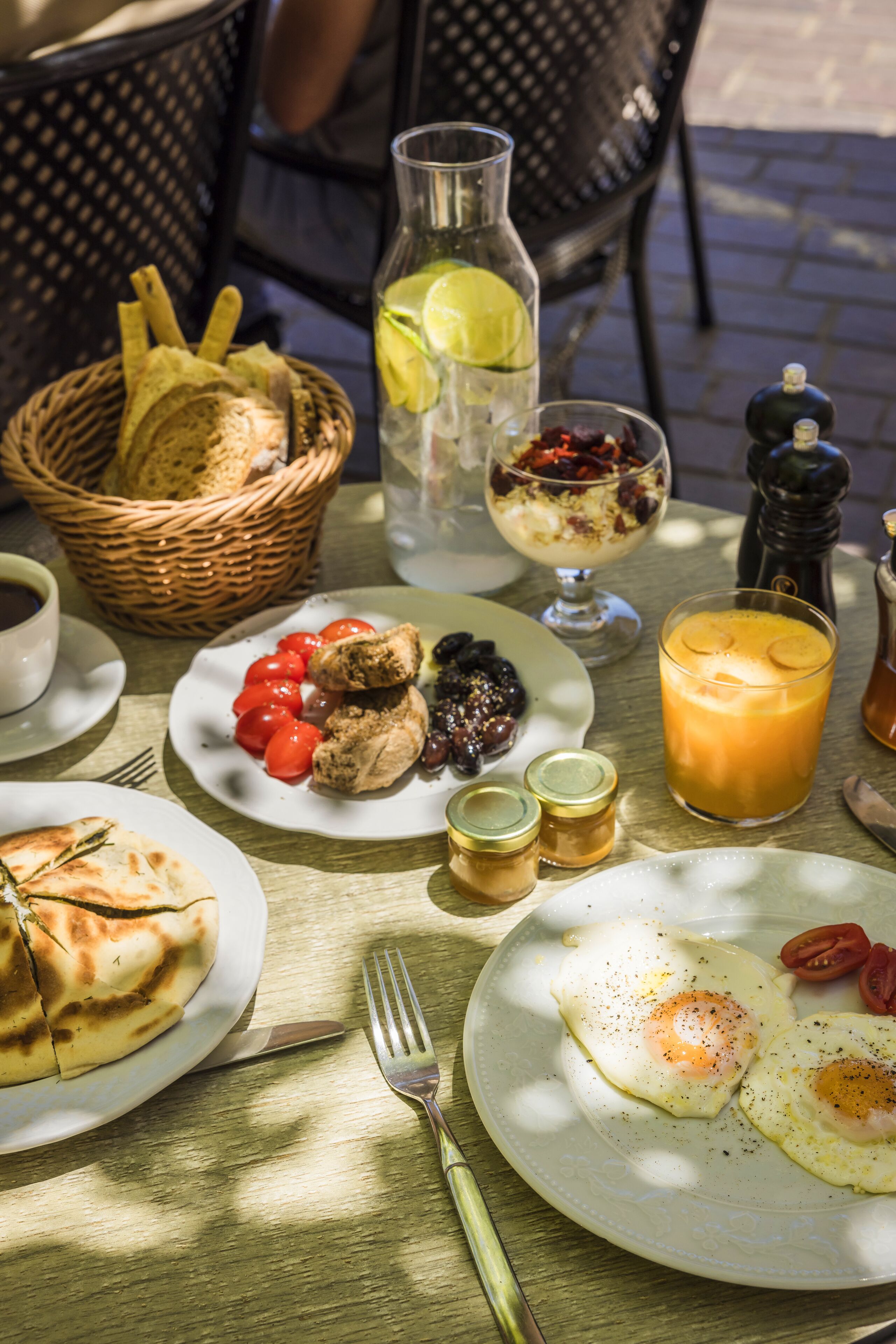 Una mesa de desayuno con platos de comida, una cesta y una botella.