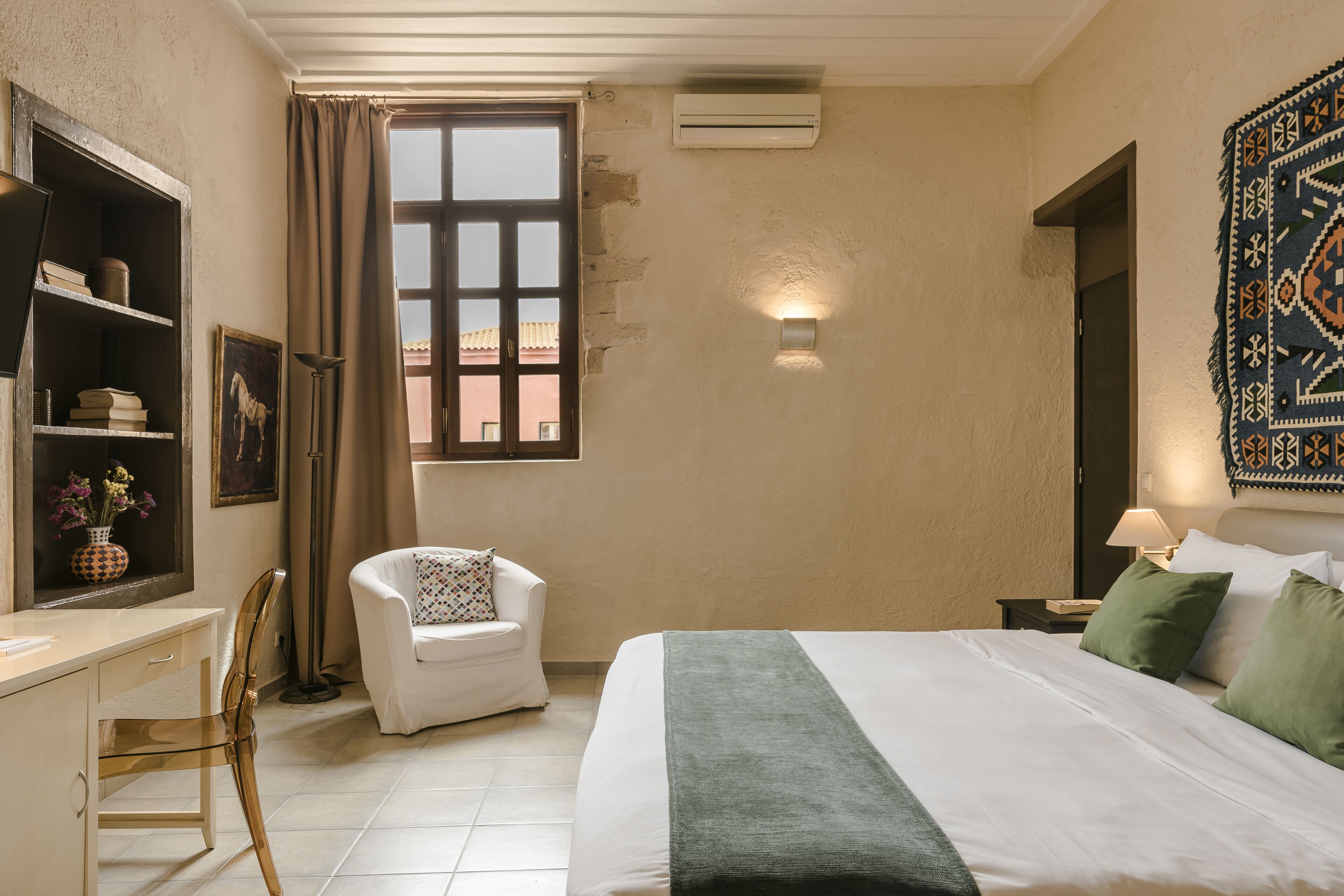 A bedroom with a bed, a desk, a chair, a window, and an air conditioning unit.
