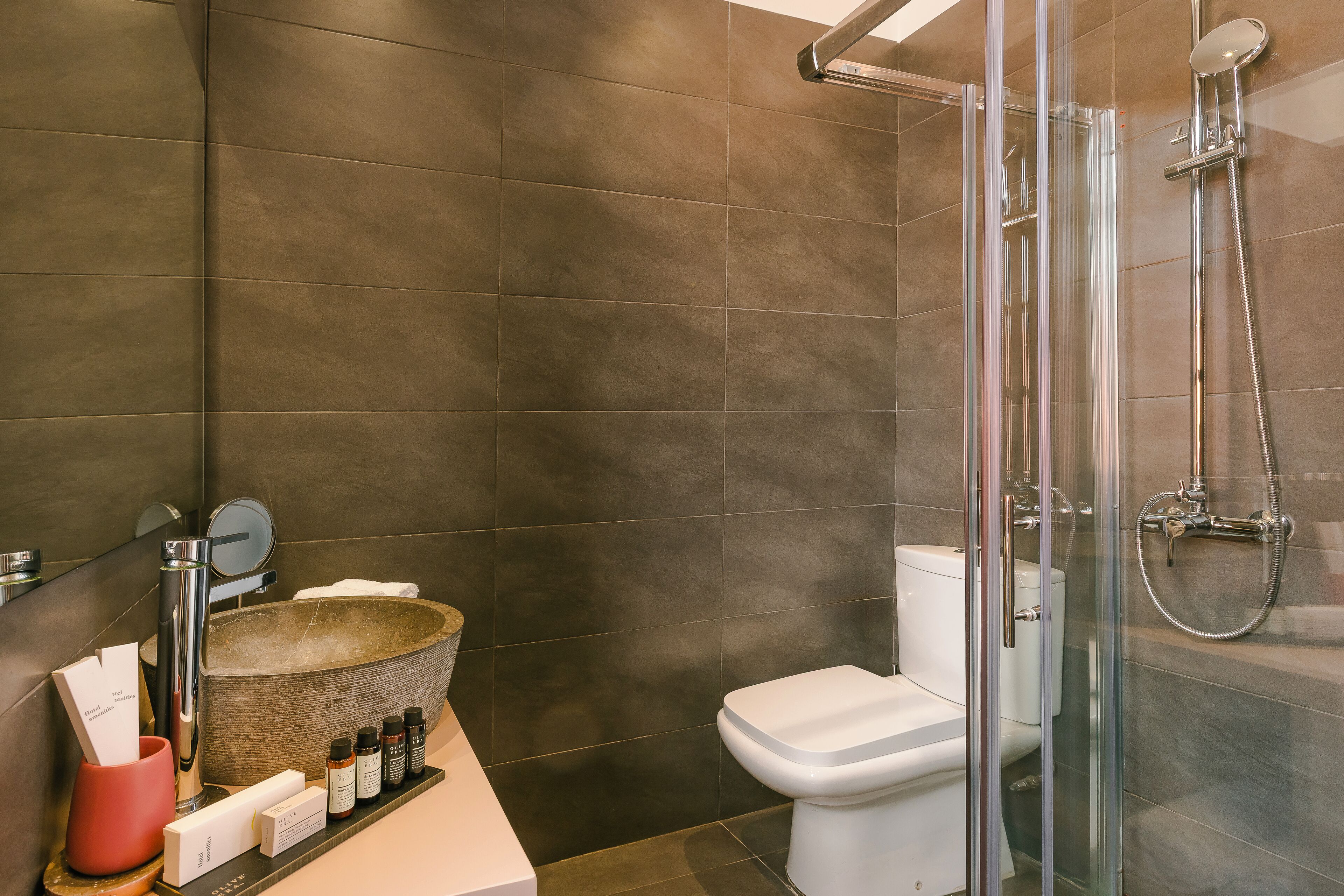 Un baño moderno con cabina de ducha de vidrio, lavabo de piedra y un inodoro blanco.