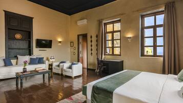 A hotel room with a bed, a sofa, a desk, and a television.