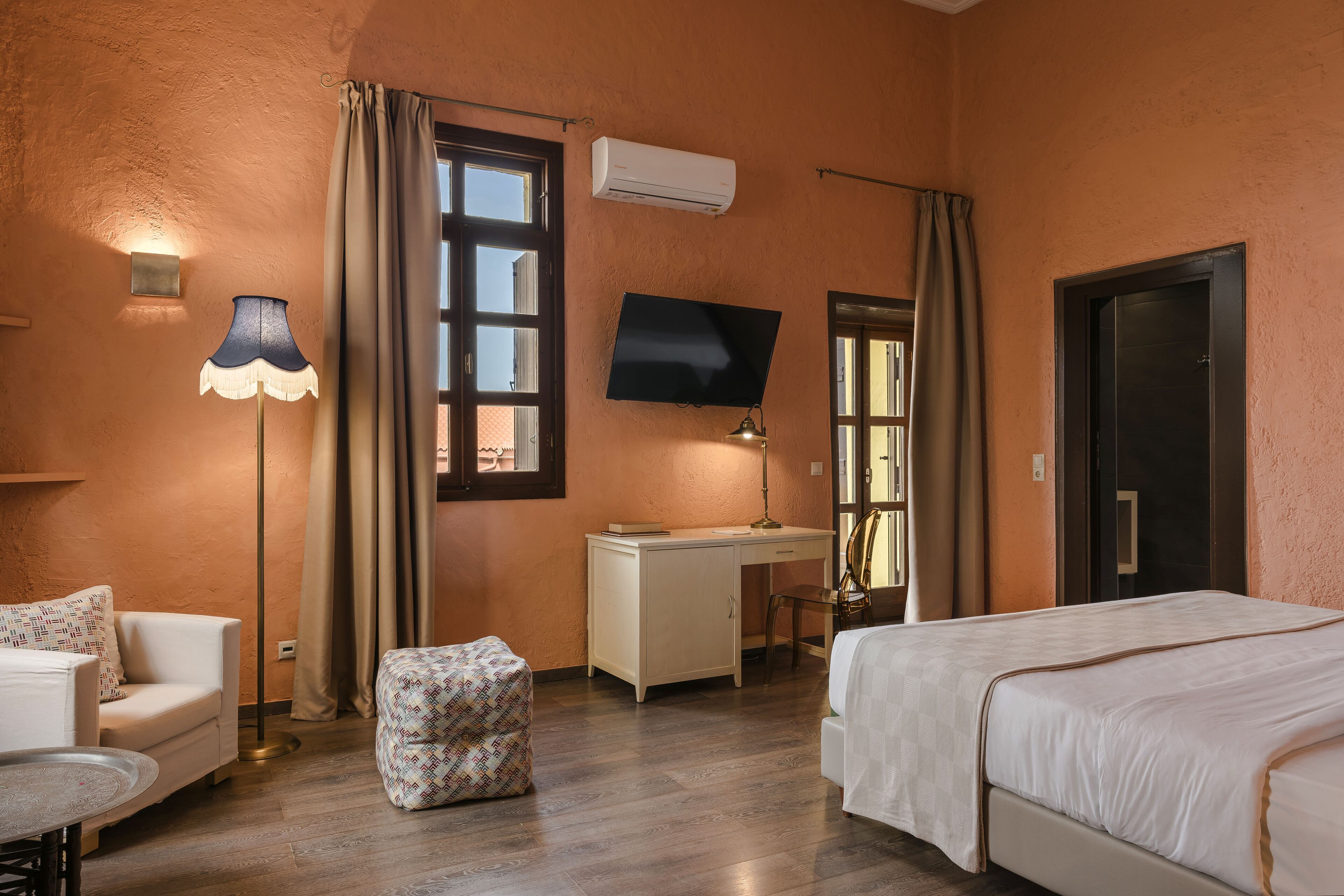 A bedroom with a bed, desk, chair, and a TV mounted on the wall.