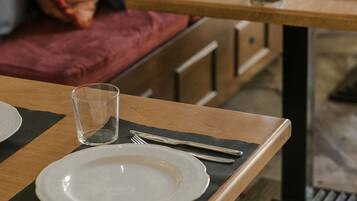 A dining area with wooden tables, black placemats, white plates, and a clear glass.