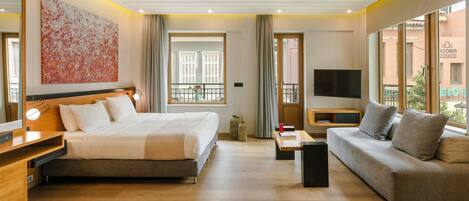 Una habitación de hotel moderna con cama, sofá, televisor y un ventanal grande.
