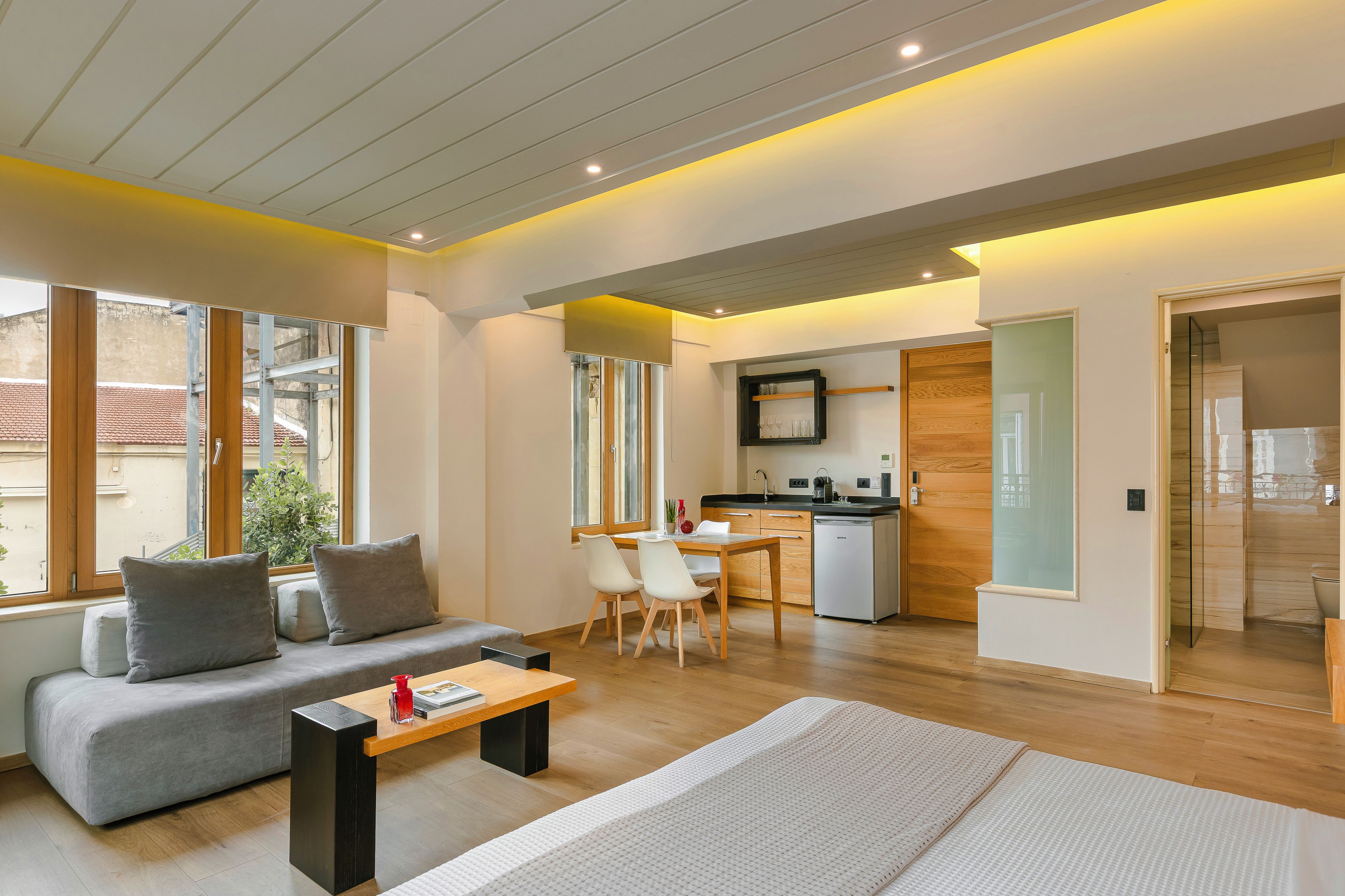A modern living room with a sofa, a coffee table, and a dining area with chairs.