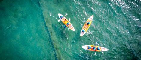 An aerial view of three kayaks on clear turquoise water.