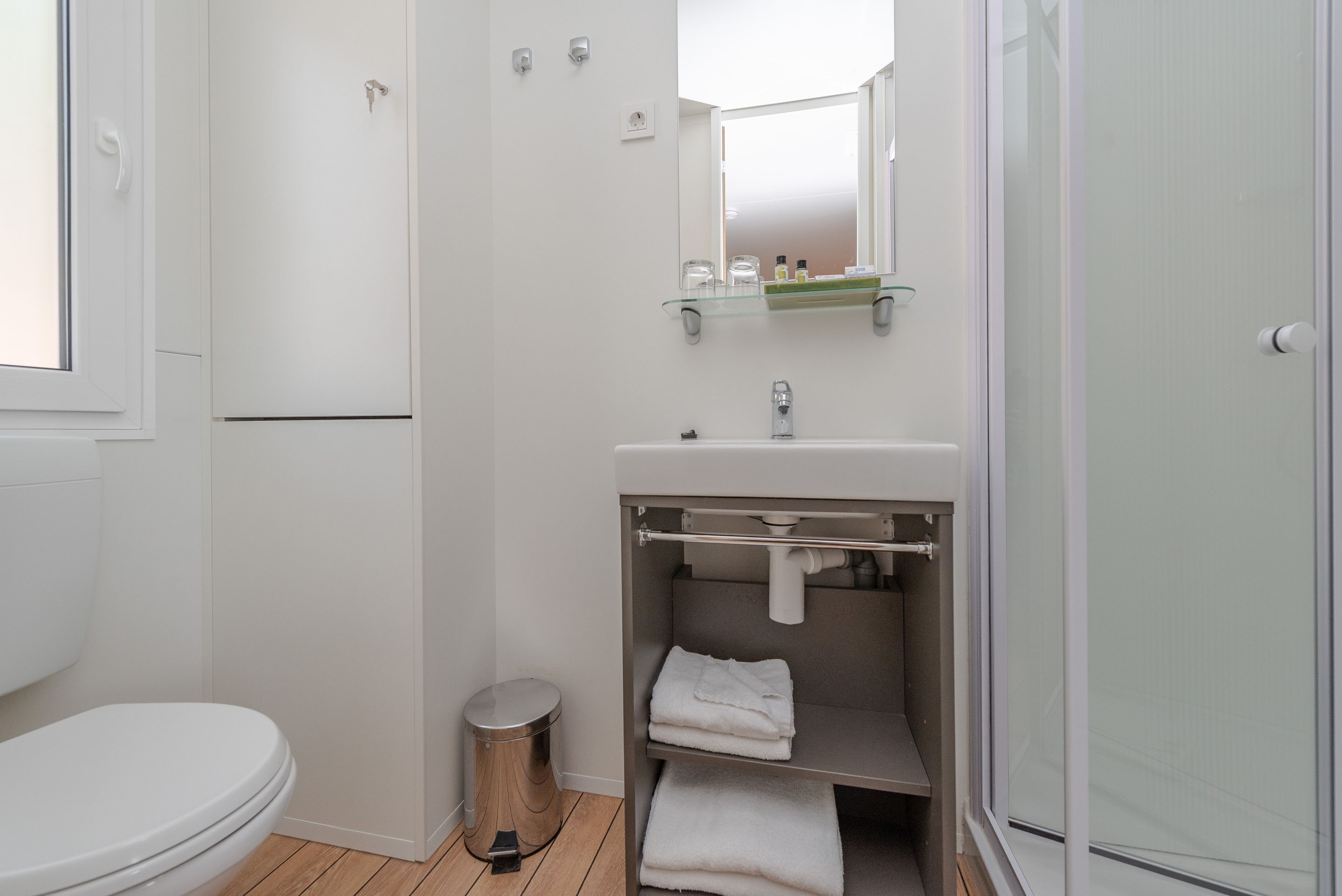 A modern bathroom with a toilet, sink, and glass shower enclosure.