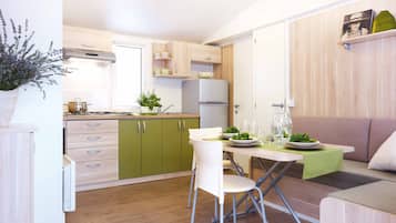 Una cocina moderna con armarios verdes, una mesa de comedor con sillas y un sofá.