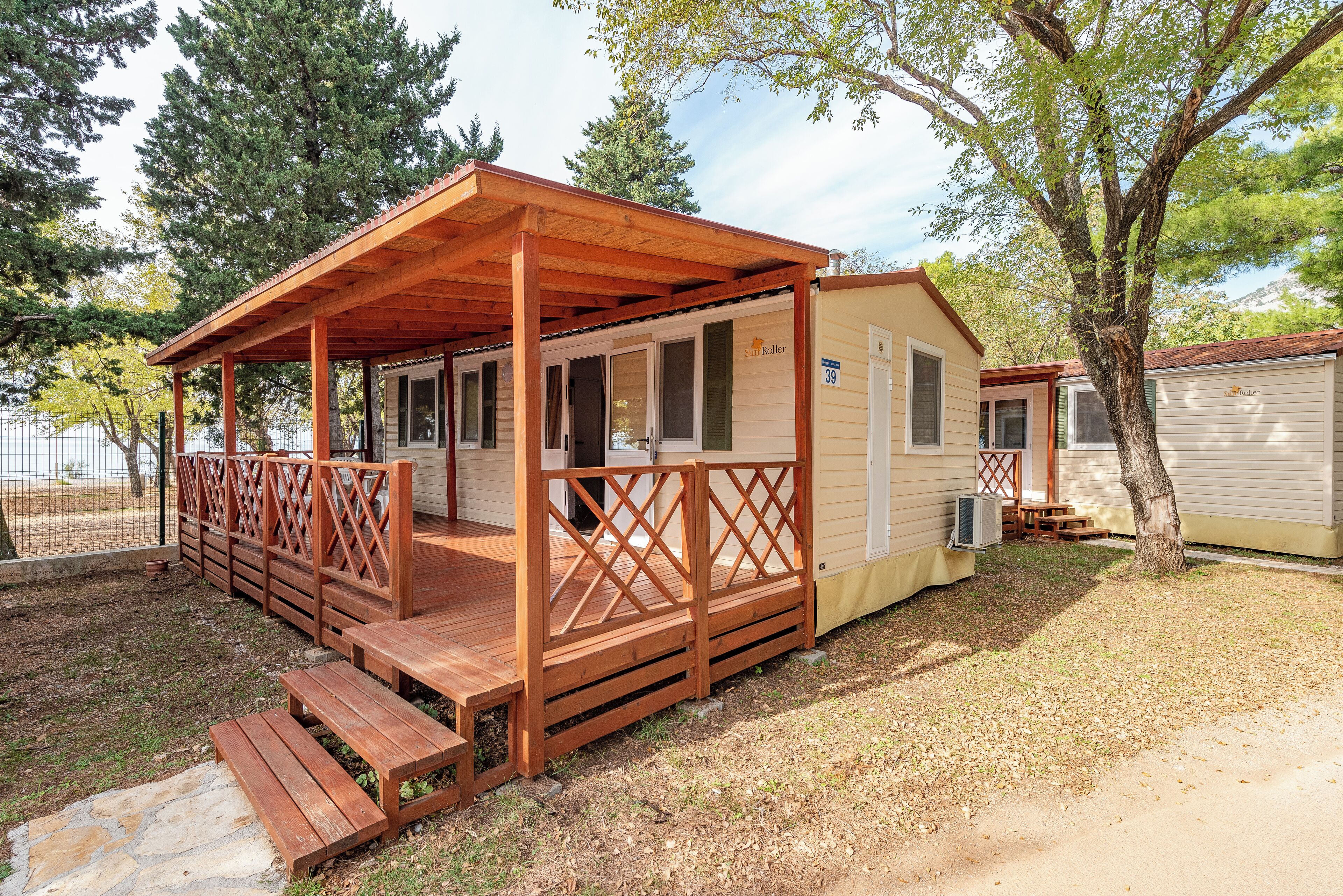 A wooden deck attached to a small cabin with a covered porch and a fenced yard.