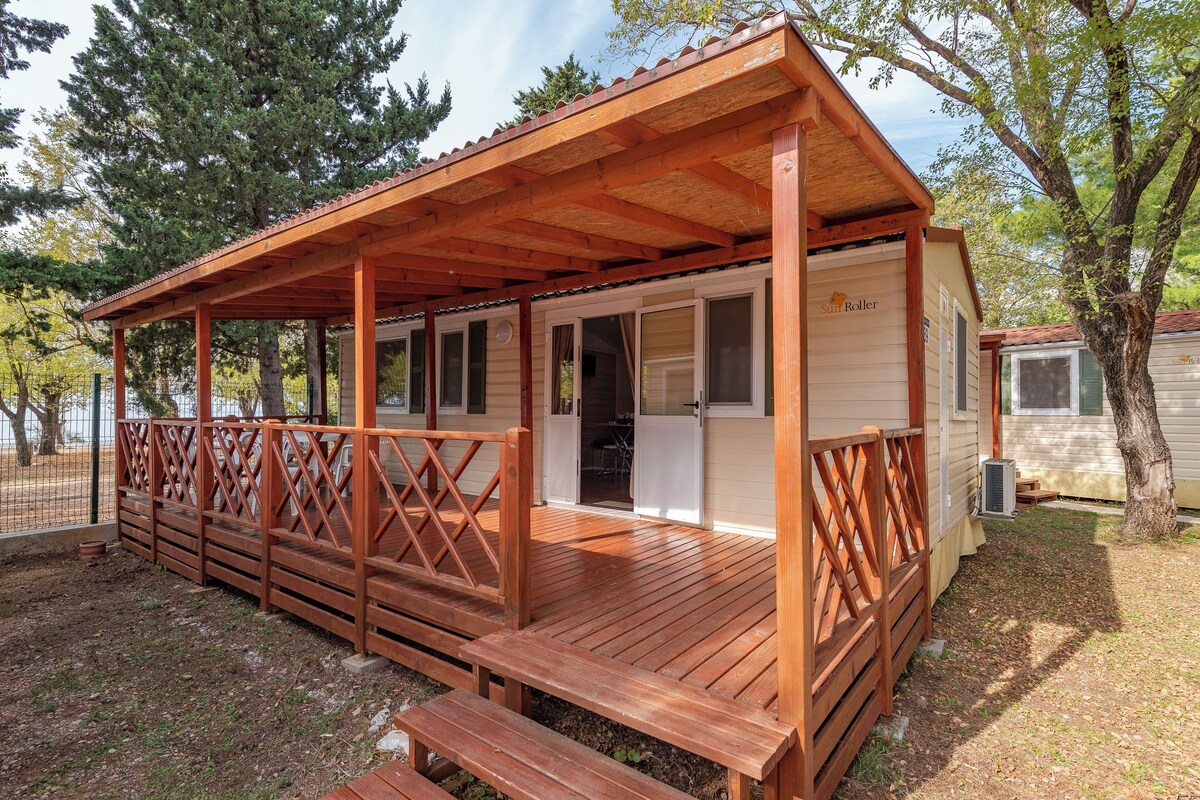 Una caravana de madera con porche cubierto y puerta corredera.