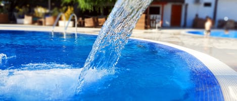 A swimming pool with clear water and a visible water spout.