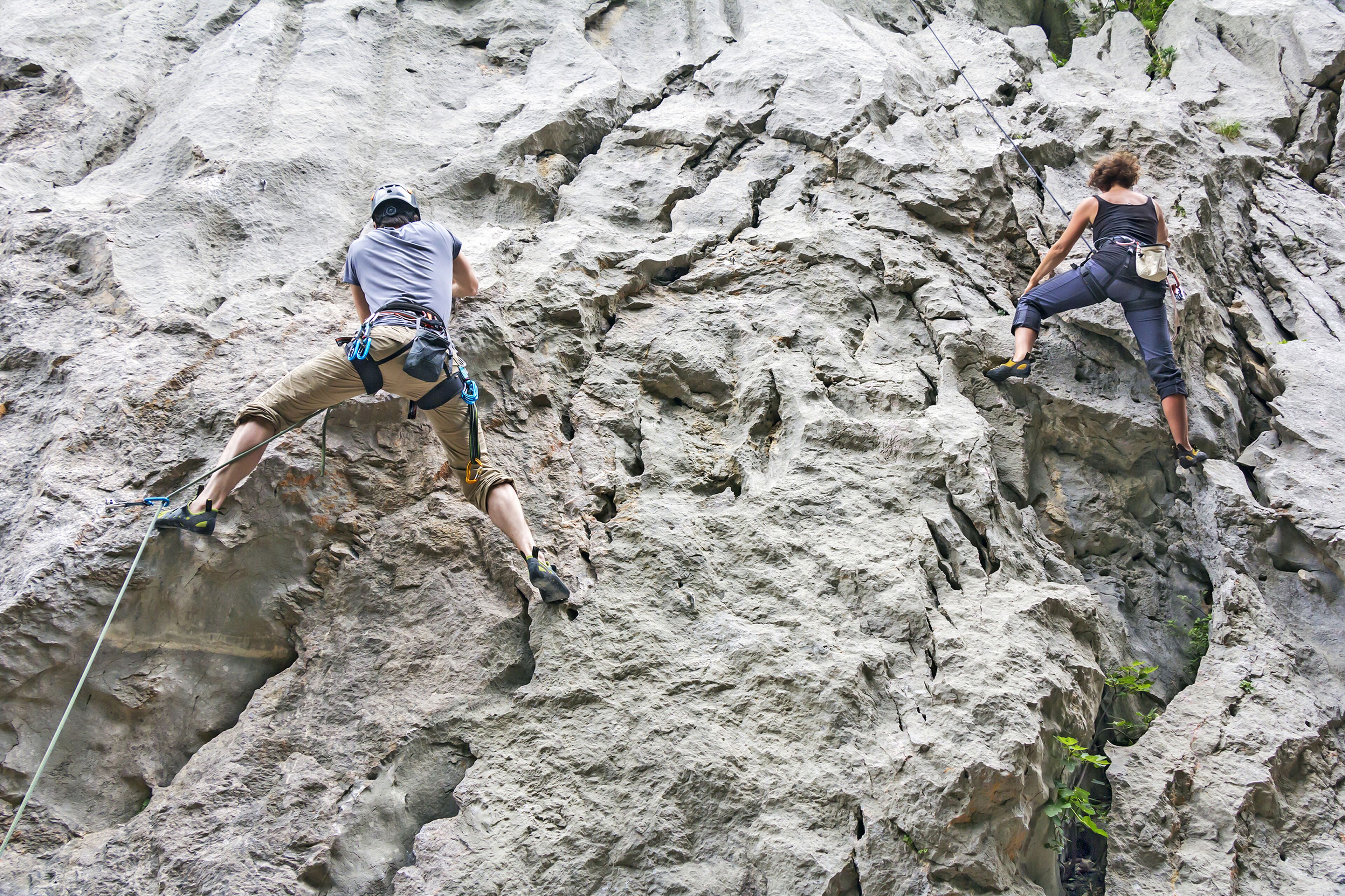 Two individuals rock climbing on a rugged cliff.