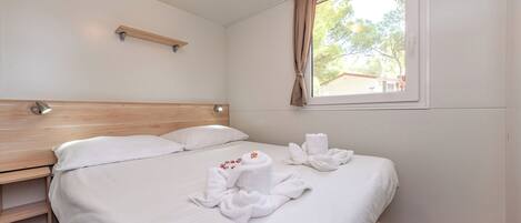 A neatly made bed with white linens and towels arranged on it.