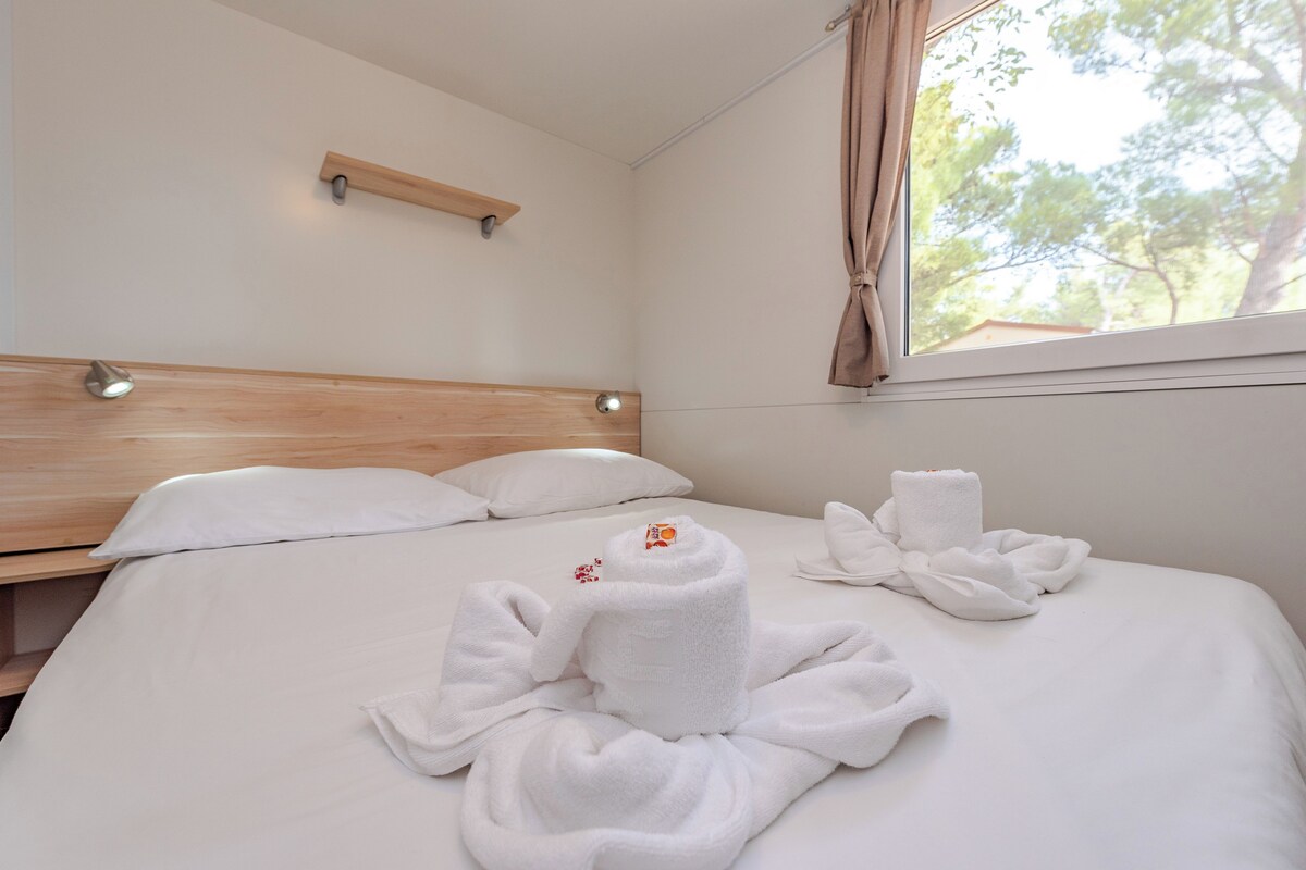 A neatly made bed with white linens and towels arranged in a decorative manner.