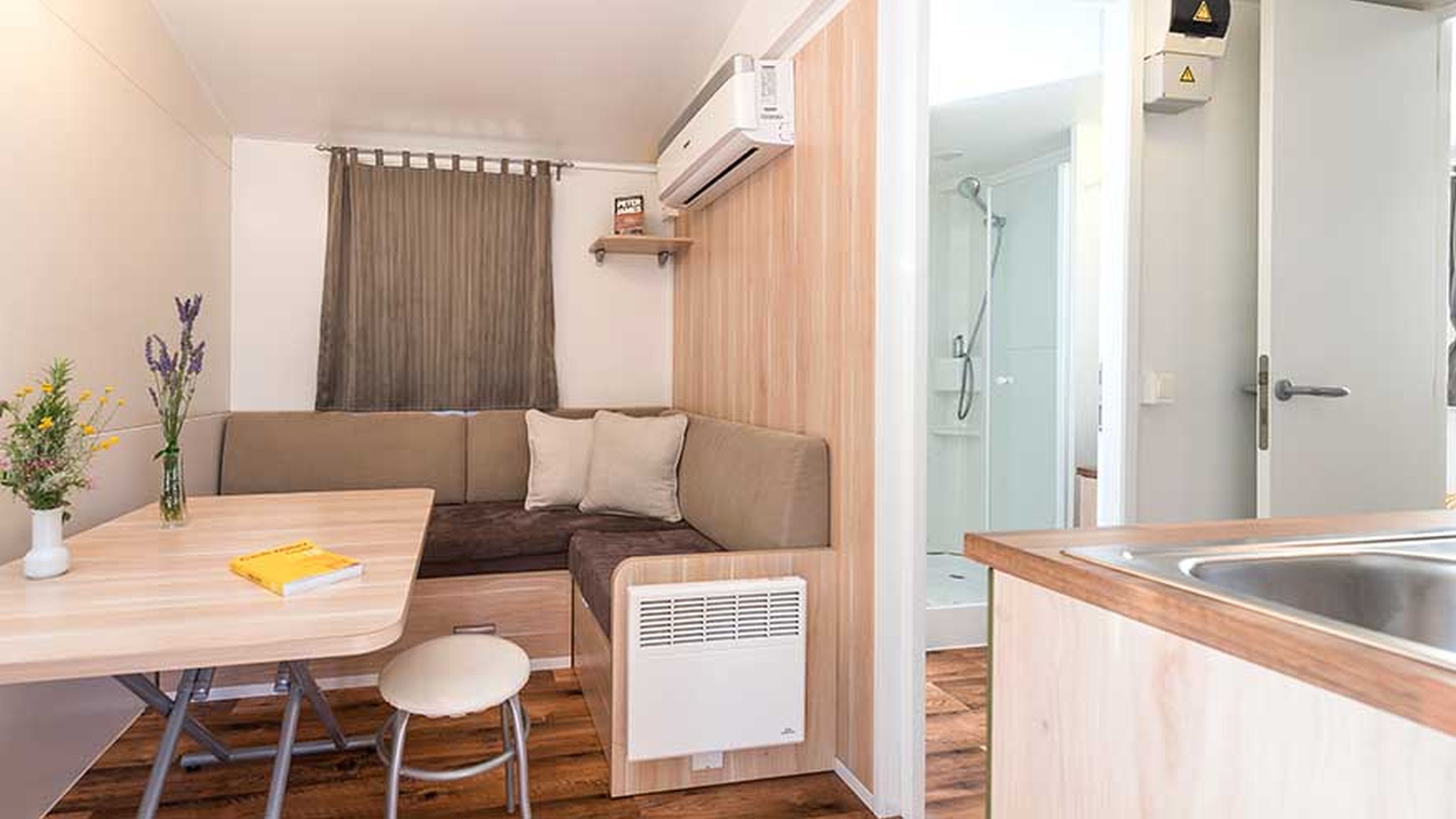 A compact living space with a kitchenette, a dining area, and a shower area.