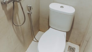 A small, compact bathroom with a toilet and a shower unit. - DS Residence Siliwangi (Semarang)