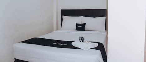 Ein Hotelzimmer mit einem Bett, einem schwarzen Kopfteil, weißer Bettwäsche und einem Handtuch auf dem Bett.