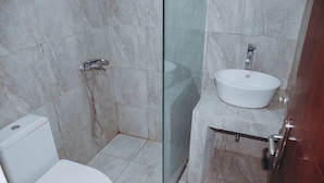 A bathroom with a toilet, a glass-enclosed shower, and a sink. - DS Residence Siliwangi (Semarang)