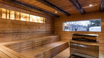 A sauna room with wooden walls, benches, and a window overlooking a snowy landscape.