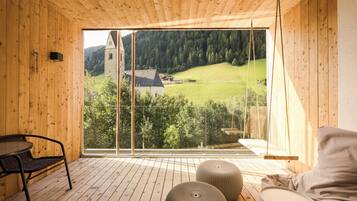 Un interior de madera con un ventanal grande que da a un paisaje verde y una torre de piedra.