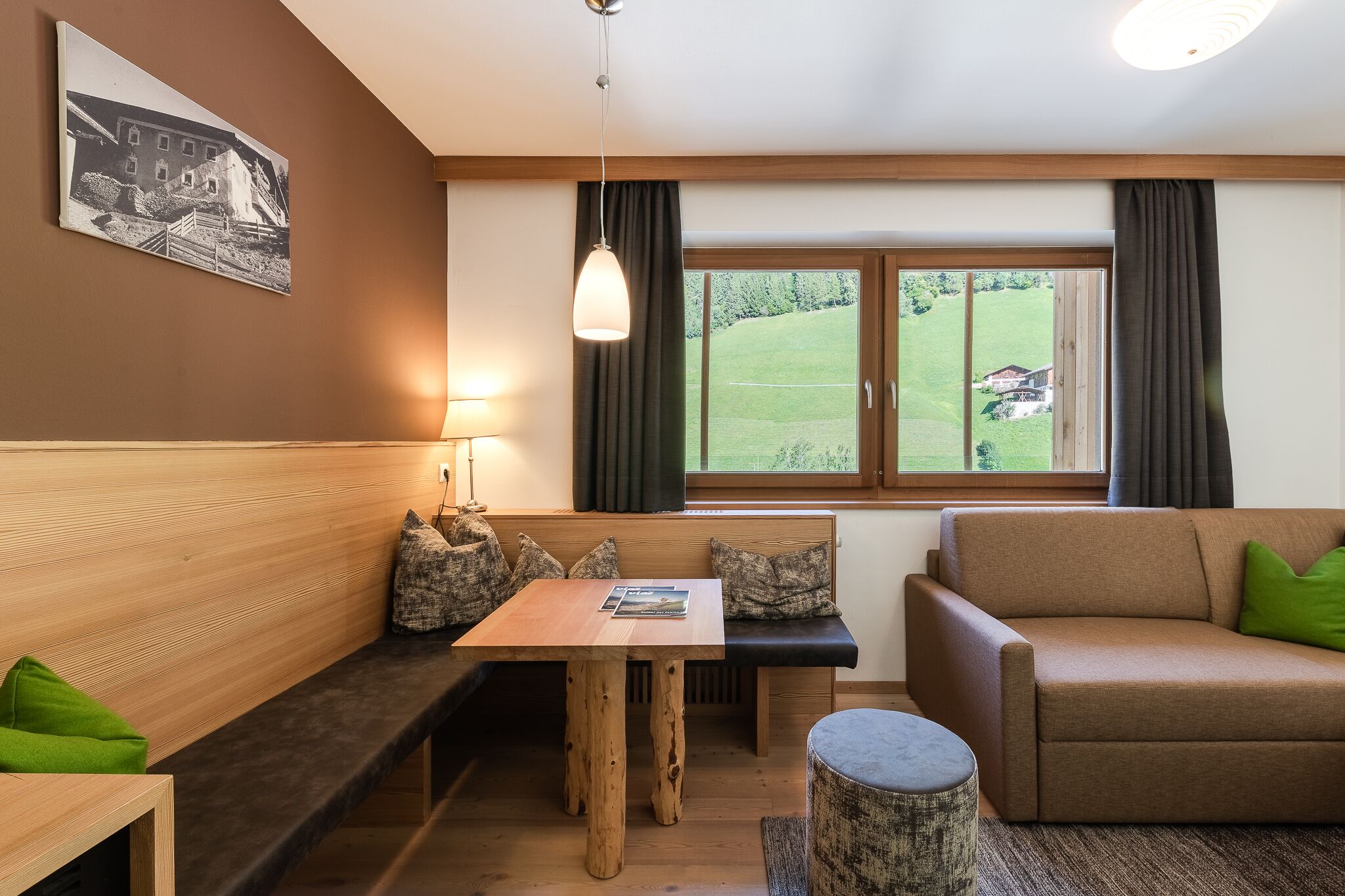 Una habitación acogedora con un banco de madera, una mesita, un sofá y una ventana con cortinas.