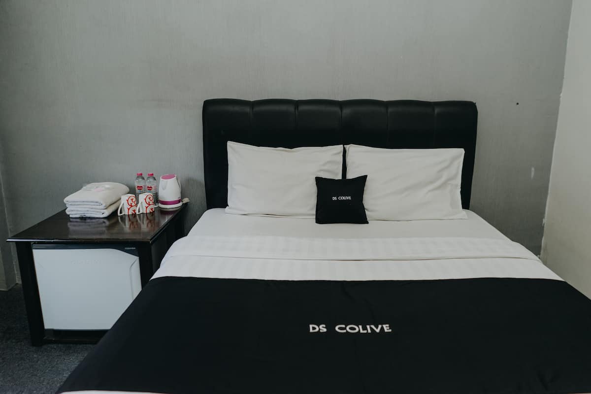 Une chambre d’hôtel avec un lit, une table de chevet et un petit réfrigérateur.