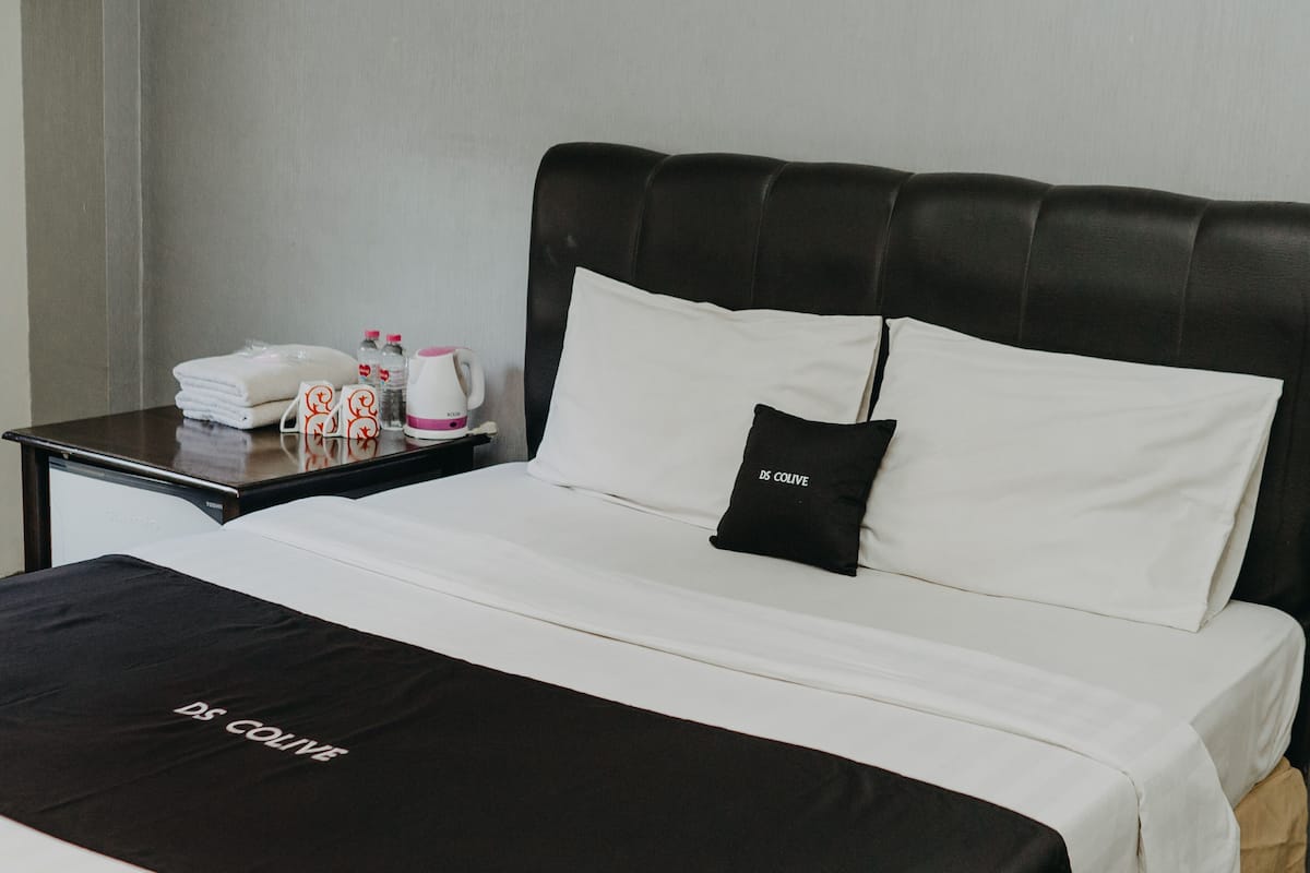 Une chambre d’hôtel avec un lit, une table de chevet avec des articles de toilette et une tête de lit noire.