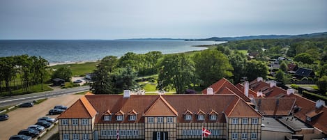 A building with a traditional architectural style, a parking area, and a view of the sea.