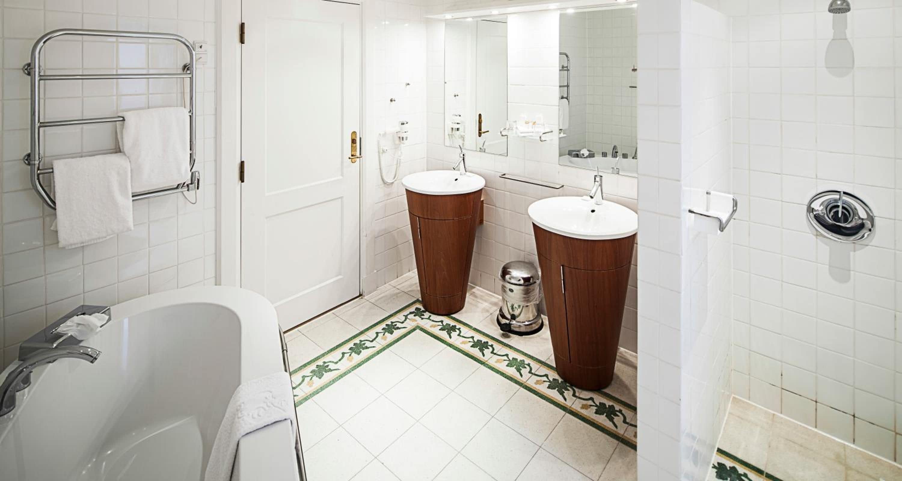 Un baño con bañera, dos lavabos, inodoro, ducha y espejo.