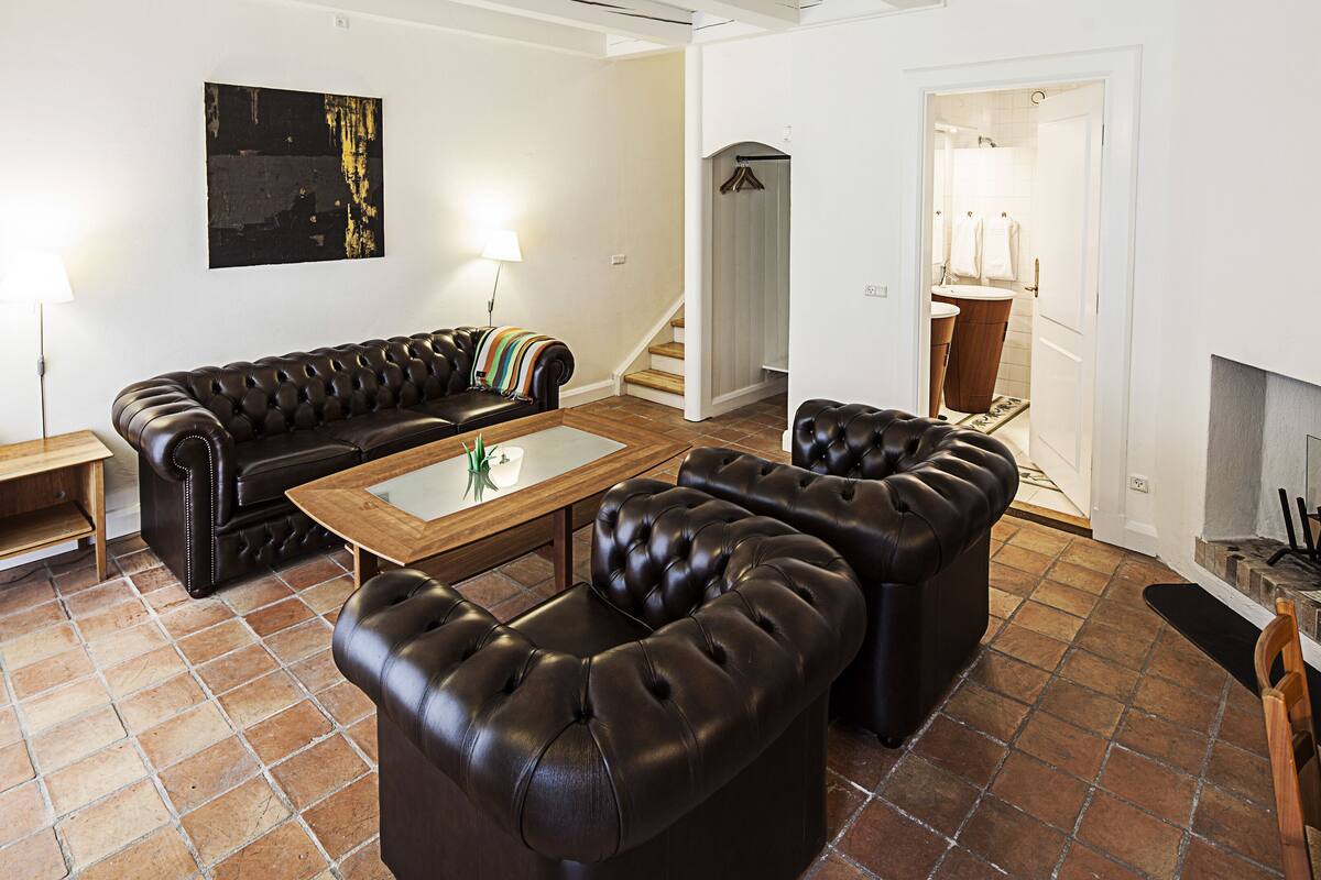 A living room with a leather sofa, a glass coffee table, and a fireplace.