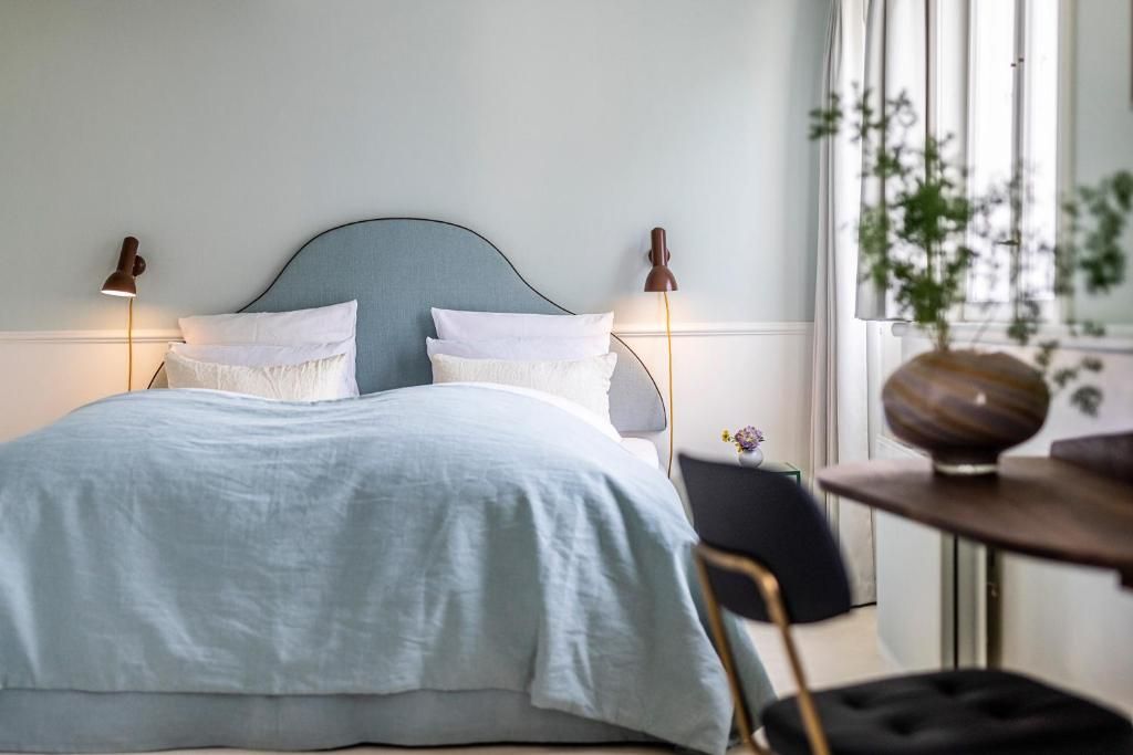 A bed with a light blue bedspread and white pillows, flanked by two wall-mounted lamps.