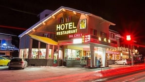 Un hôtel avec une enseigne indiquant « HÔTEL RESTAURANT DU CRET », visible la nuit.