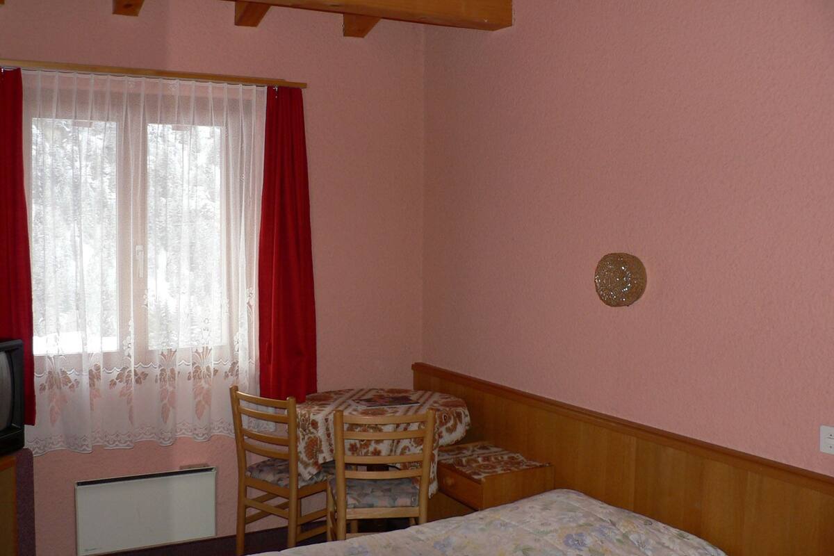 Ein Zimmer mit einem Bett, einem Schreibtisch und einem Stuhl.