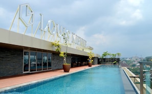 A modern hotel with a rooftop pool, large windows, and outdoor seating.
