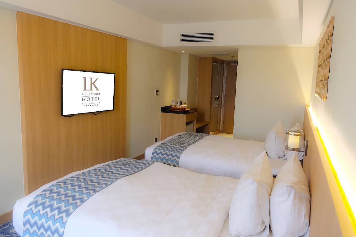 A hotel room with two beds, a wooden panel wall, a TV, a bedside table, and a mirror.